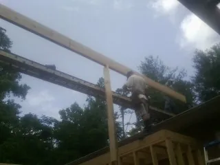 Carpenter setting a ridge beam over a new addition frame — Ice Dam Removal by Roofing Brothers in Homer