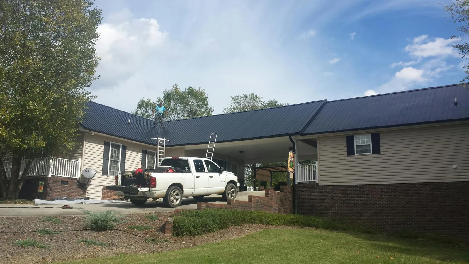 Black metal roof over a home and attached breezeway with ladders set in Homer