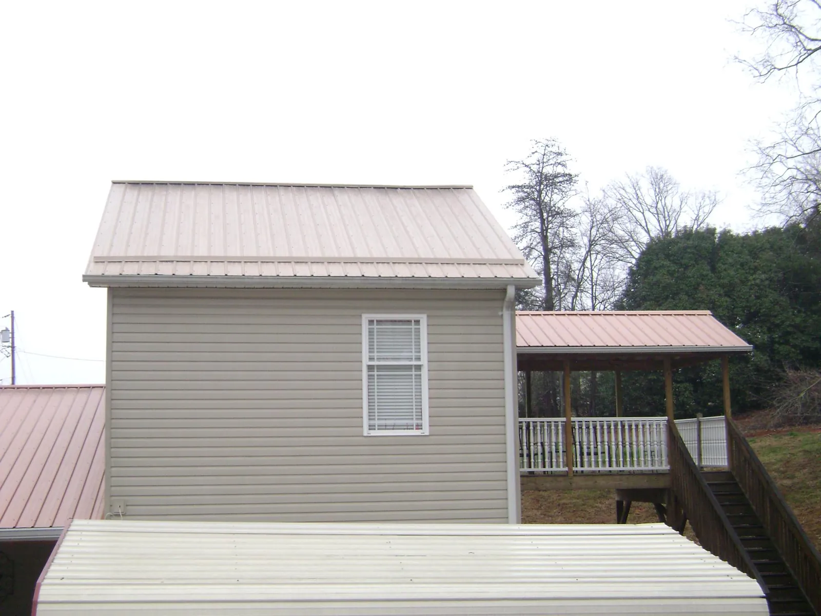 Tan metal roofs on a two story addition and attached porch, from a Roof Replacement job in Homer